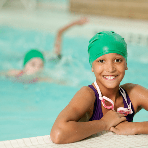 A girl in the pool with her arm around another girl.