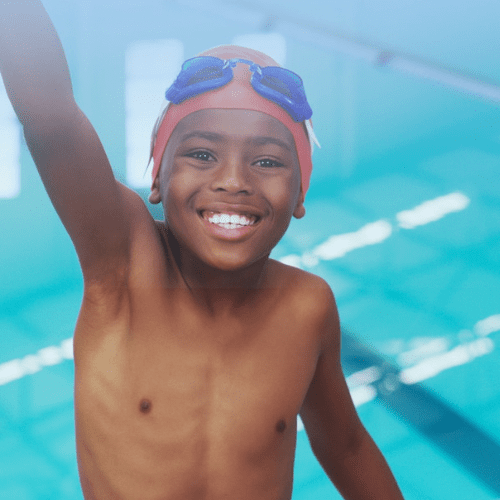 A young boy is smiling while holding his arms up.