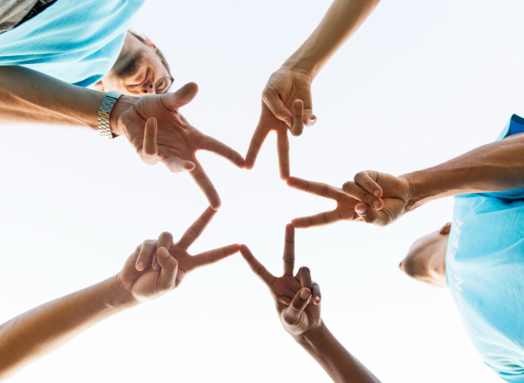 A group of people holding hands in the shape of a star.