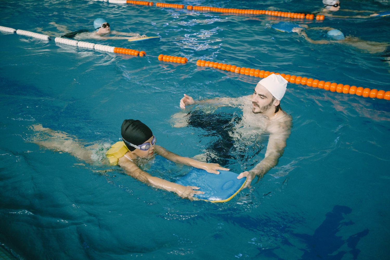 A man and boy in the pool with a boogie board.