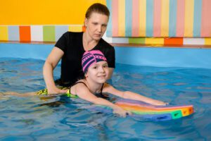 A woman and child in the pool with rainbow mats.