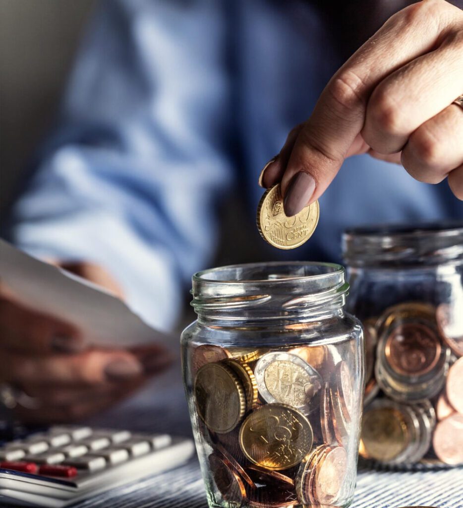 A person putting money in a jar on the table